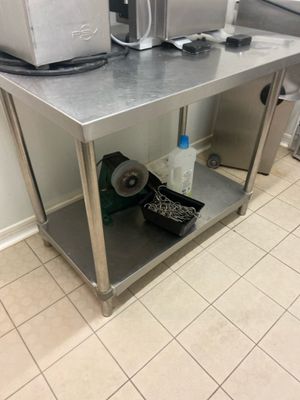 une table de travail en acier inoxydable sur laquelle sont posés deux fours à micro-ondes, dans une cuisine