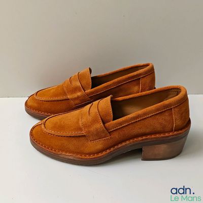 a close up of a pair of brown shoes on a white surface
