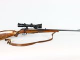 the rifle is laying on a white surface with a scope on it
