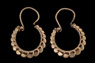 une paire de boucles d'oreilles en or sur fond noir