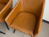 two brown chairs sitting next to each other on a tiled floor