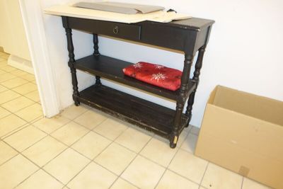 une table noire sur laquelle se trouve un plateau rouge, et une boîte posée par terre