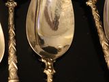 five spoons that are sitting on a black table