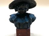 statue of a woman wearing a hat on a wooden block