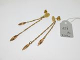 une paire de boucles d'oreilles plaquées or et une étiquette sur fond blanc
