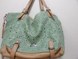 green and tan handbag hanging on a wall in a room