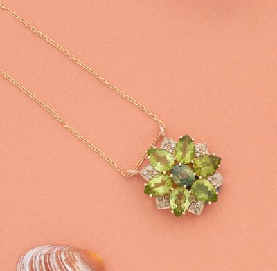 un gros plan d'un collier orné d'une fleur verte sur fond rose