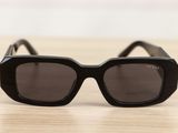 black sunglasses on a wooden table with a white wall in the background
