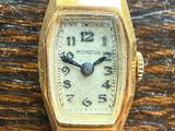 an image of a gold watch with a black strap on a wooden table