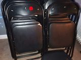 plusieurs chaises noires dans une pièce avec un bouton rouge sur le dossier