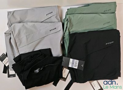 Trois paires de pantalons pour homme sont exposées sur une table