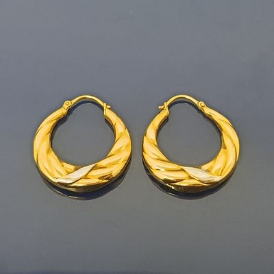 deux paires de boucles d'oreilles créoles dorées sur un fond noir