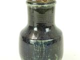 a black vase that is sitting on a white surface