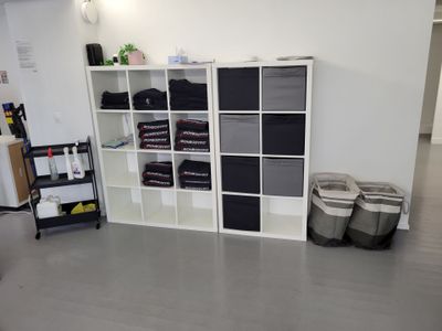 a room with a bookcase, shelves, and two bins on the floor