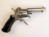 un vieux revolver argenté avec une crosse noire sur un fond blanc