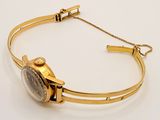 a close up of a gold bracelet with a watch on it