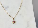 un collier plaqué or orné d'un pendentif en pierre rose posé sur un fond en marbre blanc