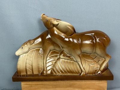 une statue représentant un cerf et un oiseau, posée sur un socle en bois