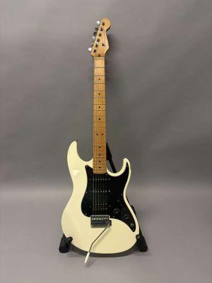 une guitare électrique blanche posée sur une surface grise