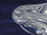 a clear glass vase with a curved handle on a blue background