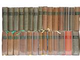 several old books are stacked on top of each other on a white surface