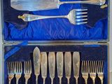 des couverts dans une boîte recouverte d'un tissu bleu, comprenant une fourchette, un couteau, une cuillère et un repose-cuillère