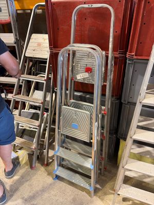 un homme qui se tient à côté d'un escabeau