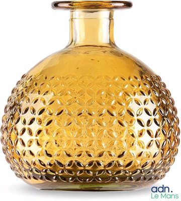 une bouteille en verre jaune avec un bouchon doré sur fond blanc