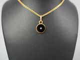 a gold necklace with a black stone pendant on a mannequin