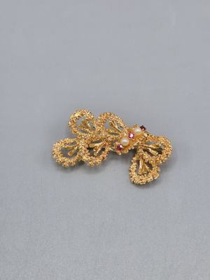 un gros plan sur une paire de boucles d'oreilles en or posées sur une surface grise