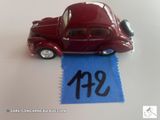 une petite voiture rouge ornée d'un ruban bleu, posée sur une table blanche