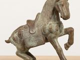 bronze statue of a horse with a saddle on it ' s back legs