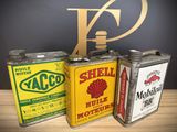 three vintage shell oil cans are lined up on a table