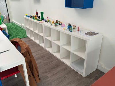 une pièce avec un bureau, des étagères et des jouets accrochés au mur