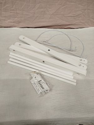 quatre cintres blancs posés sur un lit, sur lequel est accrochée une étiquette