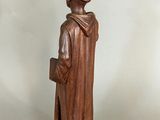 wooden statue of a monk holding a book in his hands