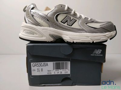 des chaussures New Balance toutes neuves, dans leur boîte, posées sur la table, avec leur étiquette de prix