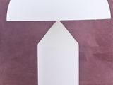 une lampe blanche posée sur une table, avec un fond rose