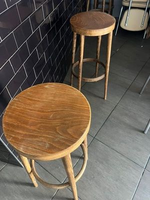 deux tabourets en bois placés l'un à côté de l'autre sur un sol carrelé
