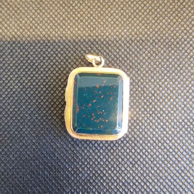 un gros plan d'un pendentif en pierre bleue posé sur une surface noire