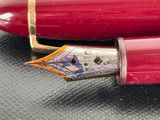 a red pen sitting on top of a black surface