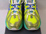 une paire de chaussures de course jaunes et bleues posée sur une boîte