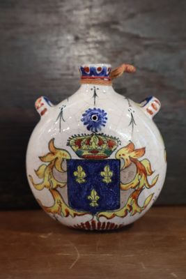 a small vase with a coat of arms on it