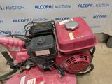 an image of a pink lawn mower sitting on the ground