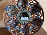 une photo représentant une assiette décorative posée sur un socle, sur une table