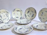 six blue and white china plates and a bowl on a white surface
