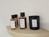 three bottles of perfume on a shelf next to a candle