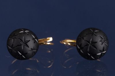 une paire de boutons de manchette noirs et dorés ornés d'un motif en forme d'étoile