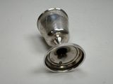 an antique silver cup with a metal handle on a white surface