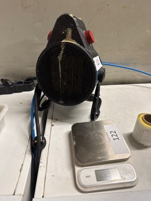 une photo d'un radiateur d'appoint posé sur une table, à côté d'un mètre ruban et d'une bobine de fil